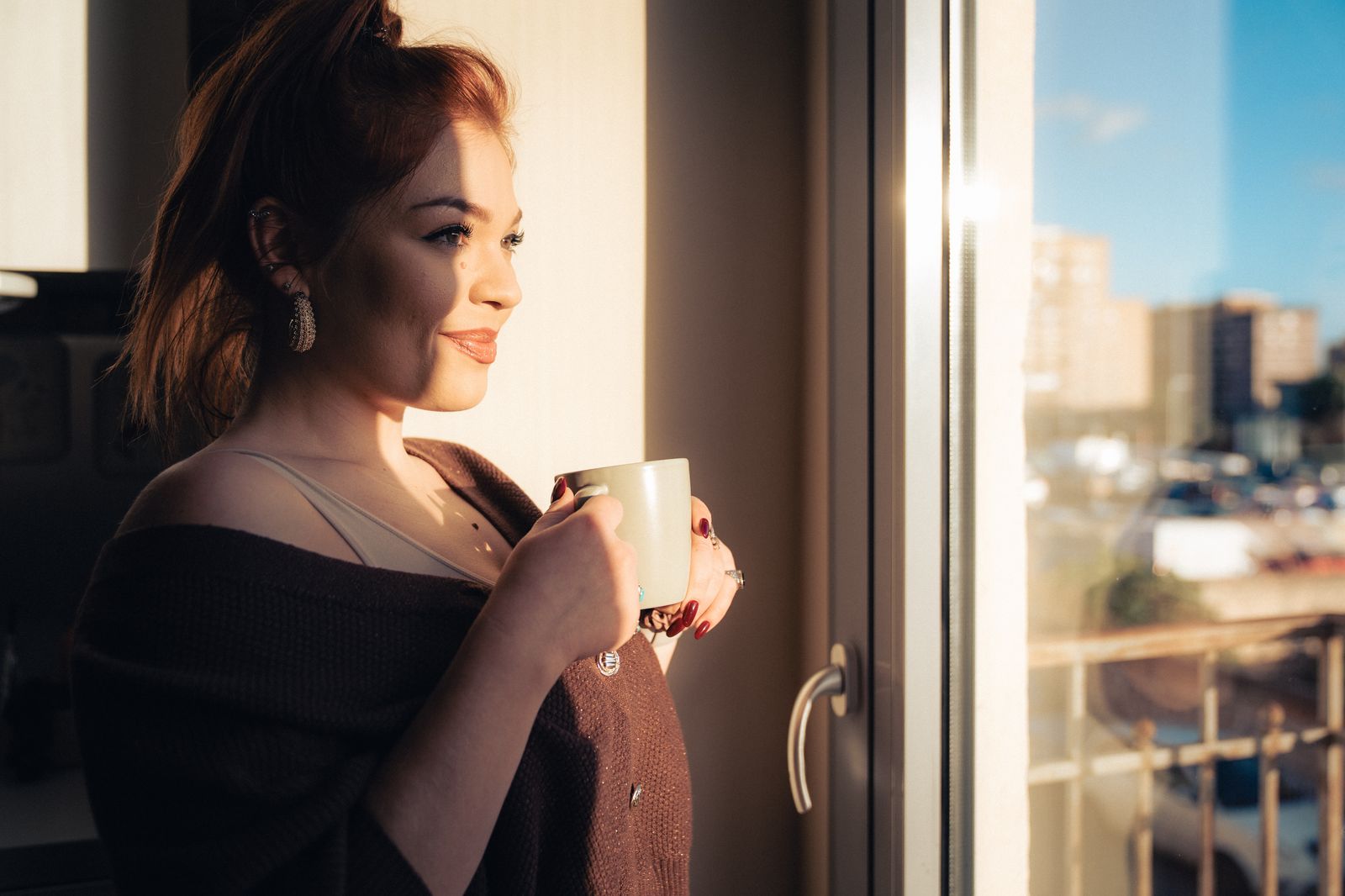 Woman pausing with a coffee at the window