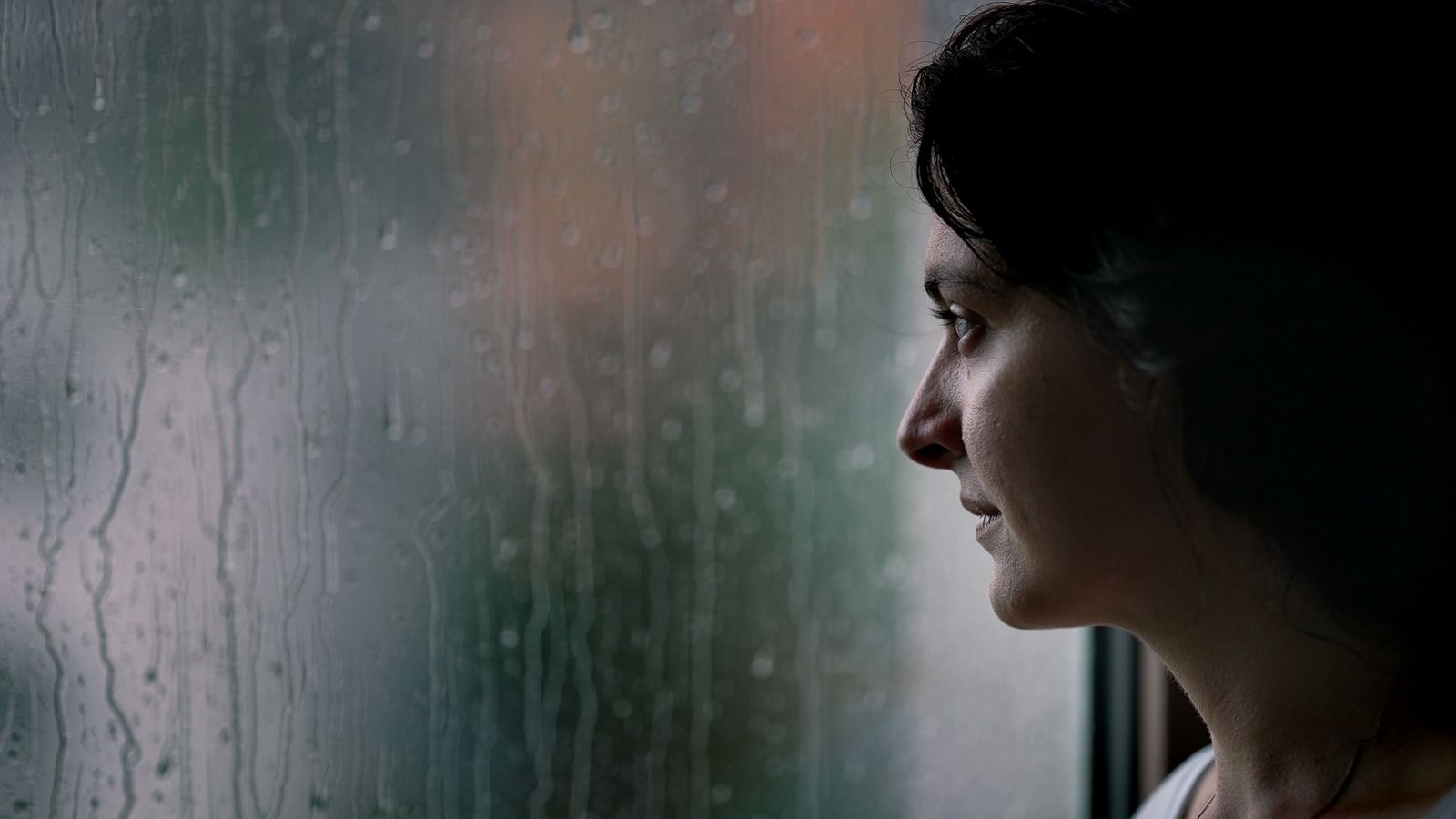 Woman watching rain on the window
