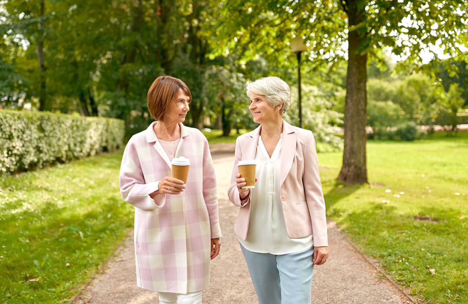 Two friends walking and talking with coffee